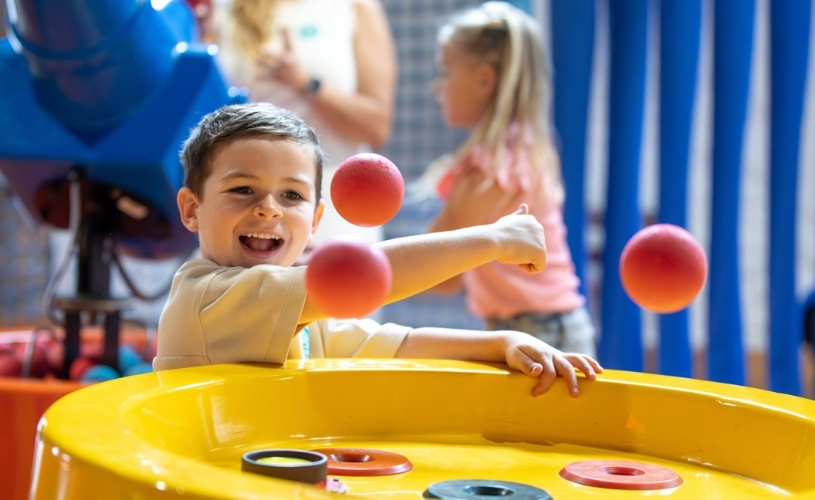 A young boy playing with floating play balls at Wookey Hole